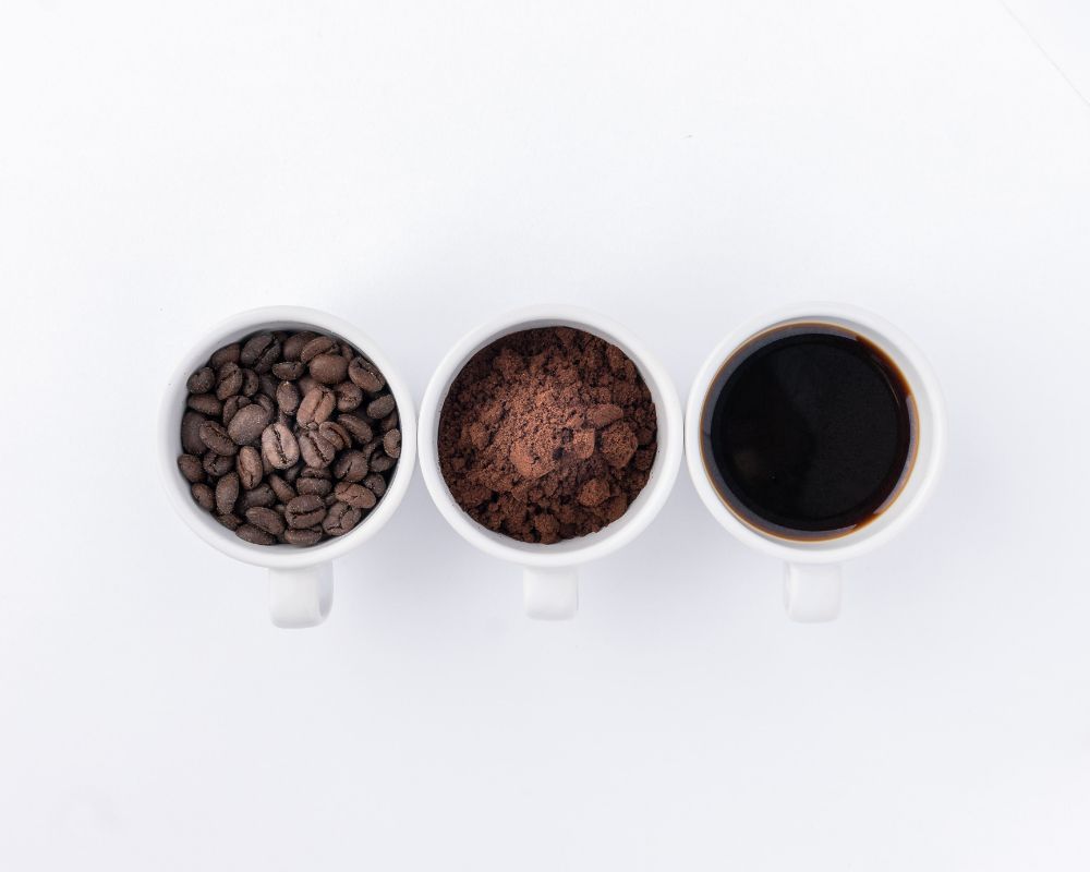 Overhead view of three white coffee cups lined up side-by-side on white surface.
